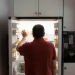 Personne vérifiant la température intérieure d'un réfrigérateur ouvert